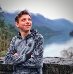 Thoughtful teenage boy standing against mountains