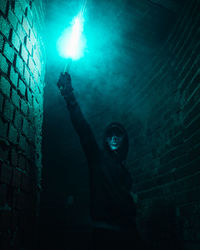 Portrait of woman standing against illuminated wall