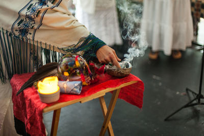 Midsection of man holding lit candles in temple