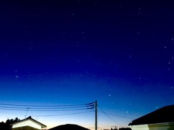 Low angle view of electricity pylon against sky at night