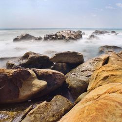 Scenic view of rocks in sea against sky