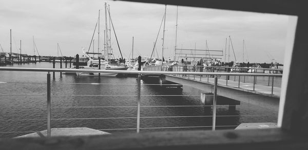 Sailboats on pier at harbor against sky