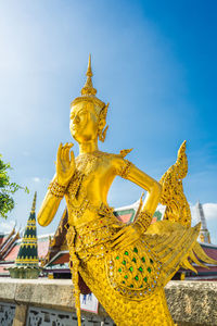 Low angle view of statue against temple building against sky