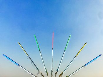 Low angle view of colorful fishing rods against clear blue sky