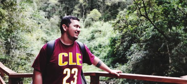 Portrait of young man standing against trees