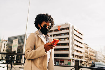 Young man using smart phone against sky