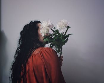 Close-up of woman with flower against white background