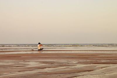 Man on beach against clear sky