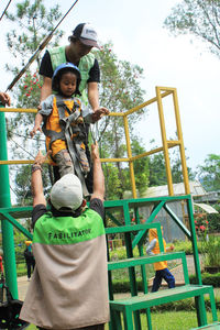 Father and son standing on tree against sky