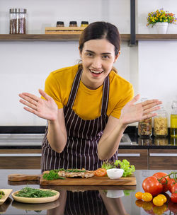 Portrait of smiling woman with vegetables at home