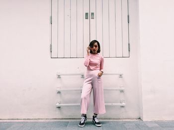 Portrait of young woman standing against wall