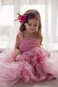 Portrait of a girl in a pink dress and a flower with a rose in her head in the studio