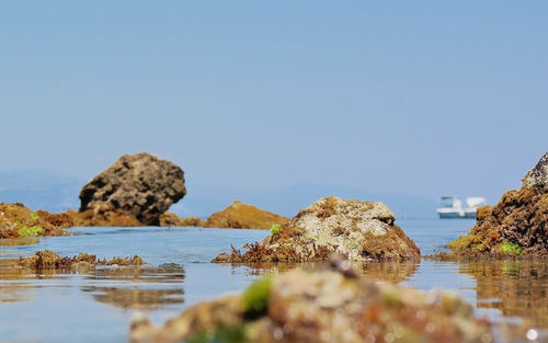 Rocks in sea against clear sky