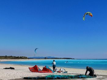 People enjoying at beach against clear sky