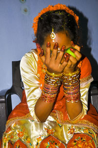 Girl covering face while sitting on chair at home