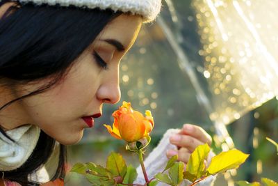 Close-up of young woman smelling rose at garden