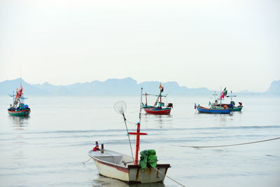 Fishing boats moored in sea against clear sky