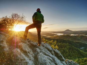 Man walking on the edge. climber enjoying beautiful nature view at sunset after challenging climb
