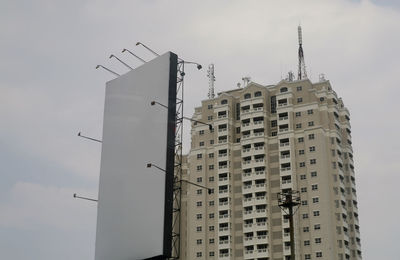 Low angle view of building and billboard against sky