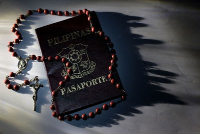 Close-up of passport and rosary on table