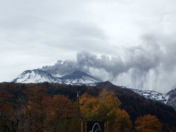 Scenic view of snow covered mountains against cloudy sky