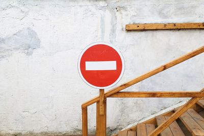 Close-up of information sign on railing against wall