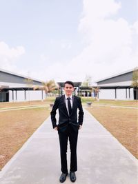 Full length portrait of young man standing against sky