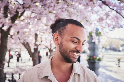 Smiling young man standing under cherry blossom