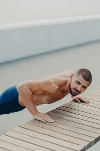 Portrait of shirtless young man exercising outdoors