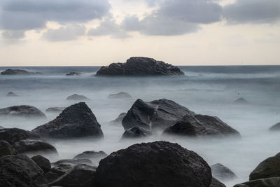 Scenic view of rocks in sea against sky