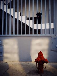 Rear view of man sitting on footpath against building