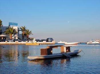 Boats moored in sea against clear blue sky