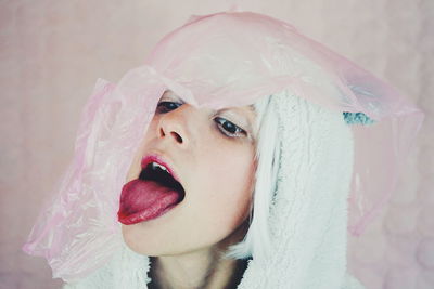 Close-up of woman in costume with pink plastic against wall