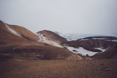 Glacier by mountains against clear sky