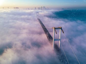 Aerial view of bridge amidst cloudy during sunset