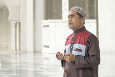 Man with necklace standing in mosque