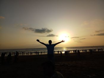 Silhouette man standing on beach against sky during sunset
