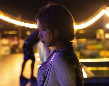 Rear view of woman with arms raised standing at night