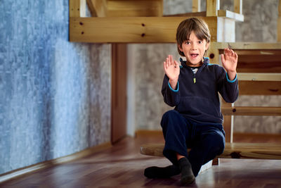 Full length of cute boy sitting on hardwood floor