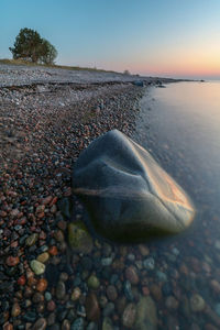 Surface level of stones on beach against sky during sunset