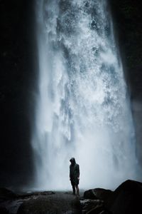 Man standing on rock against waterfall