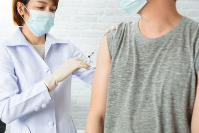 Doctor wearing mask vaccinating patient