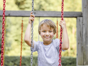 Portrait of smiling boy on swing at playground