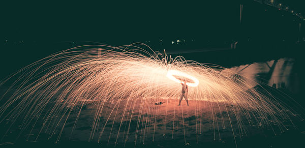 Man performing wire wool with fire at night