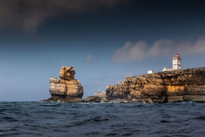 Lighthouse by sea against buildings