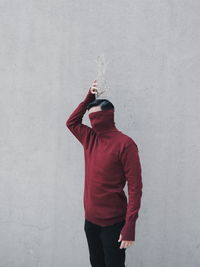 Man holding decor on head standing against wall