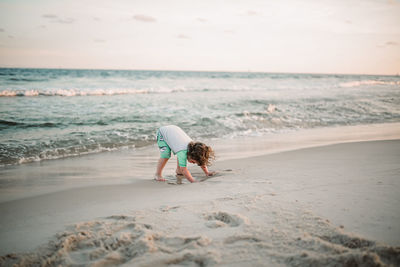 Rear view of boy on beach against sky