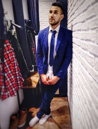 Portrait of young man standing against wall