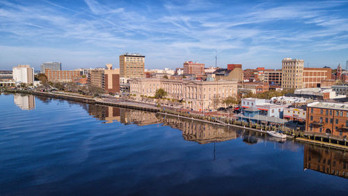 Reflection of buildings in river against sky