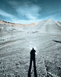 Rear view of man on snowcapped mountain against sky